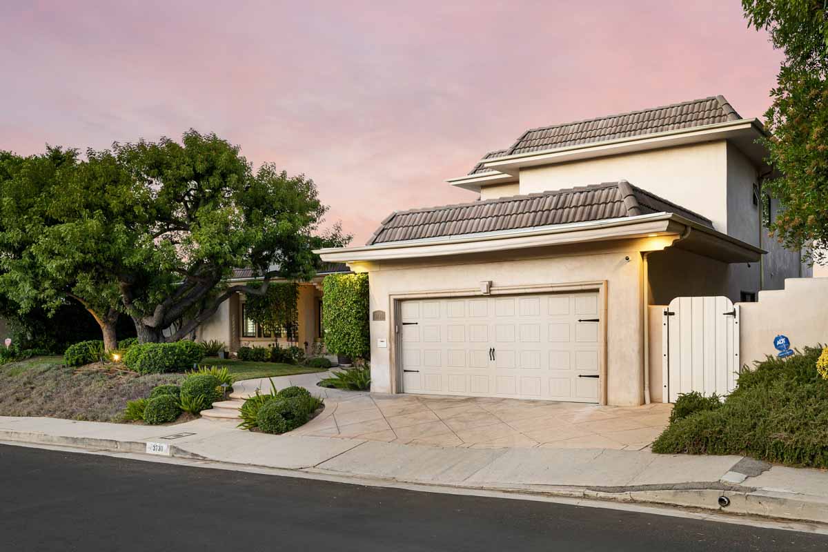 A driveway bordered by numerous trees and shrubs in Encino, California